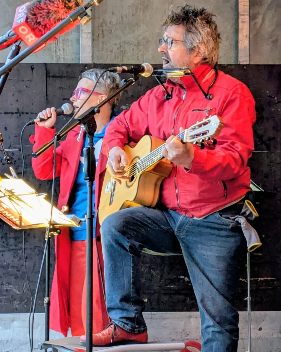 Zwei Musiker auf der Bühne, einer mit Gitarre, beide singen