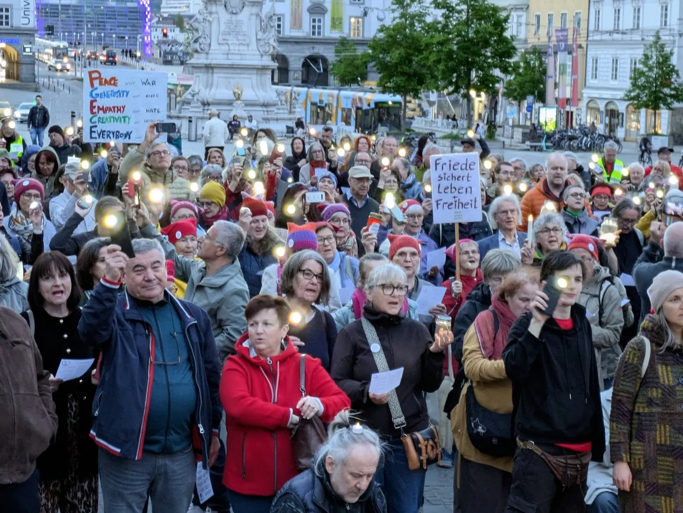 Viele Menschen halten Handylichter in die Höhe, auf einem Schild steht: Friede sichert Leben und Freiheit