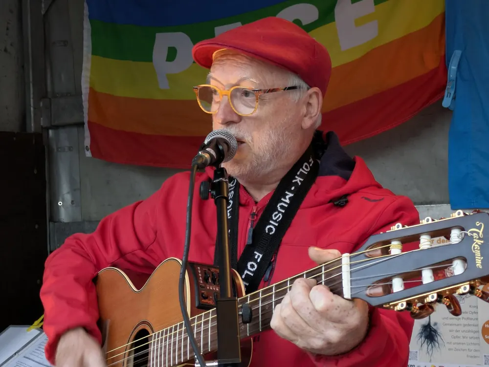 Ein Sänger mit roter Kappe und Gitarre singt ins Mikrofon
